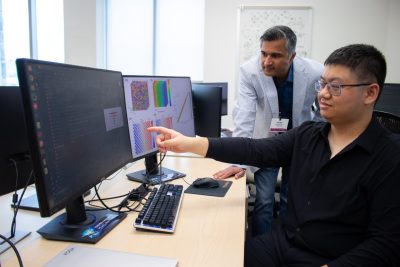Researchers gathered around a computer screen analyzing research.