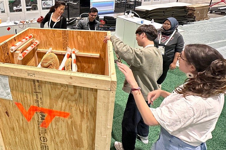 Students and professors unbox a HokieBird made of stacked corrugated cardboard