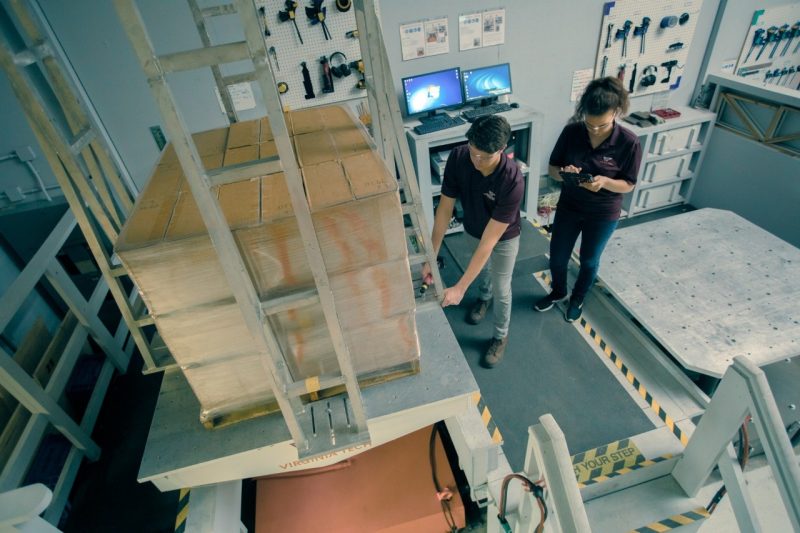Students in a lab testing packages in a machine that simulates various transportation vibrations