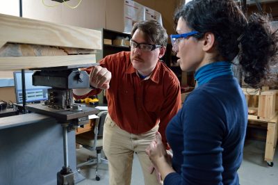 A professor and graduate student inspect a crack in wood made from a testing machine