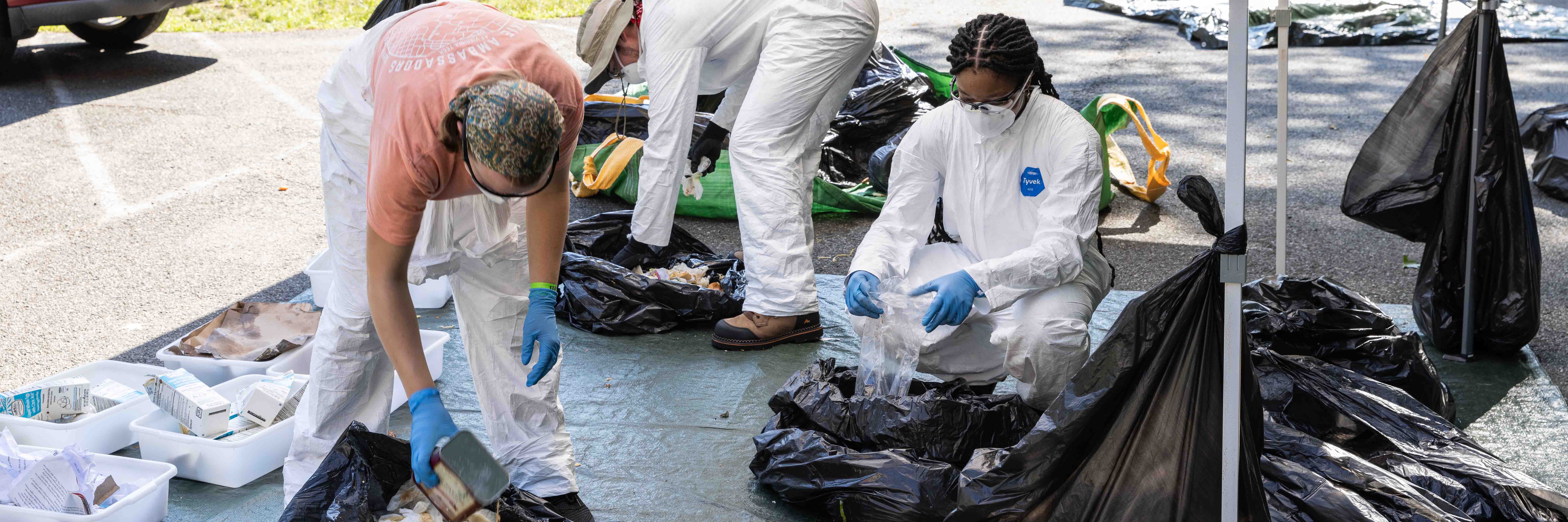 Researchers in a parking lot sorting through trash bags into waste and recycling.  