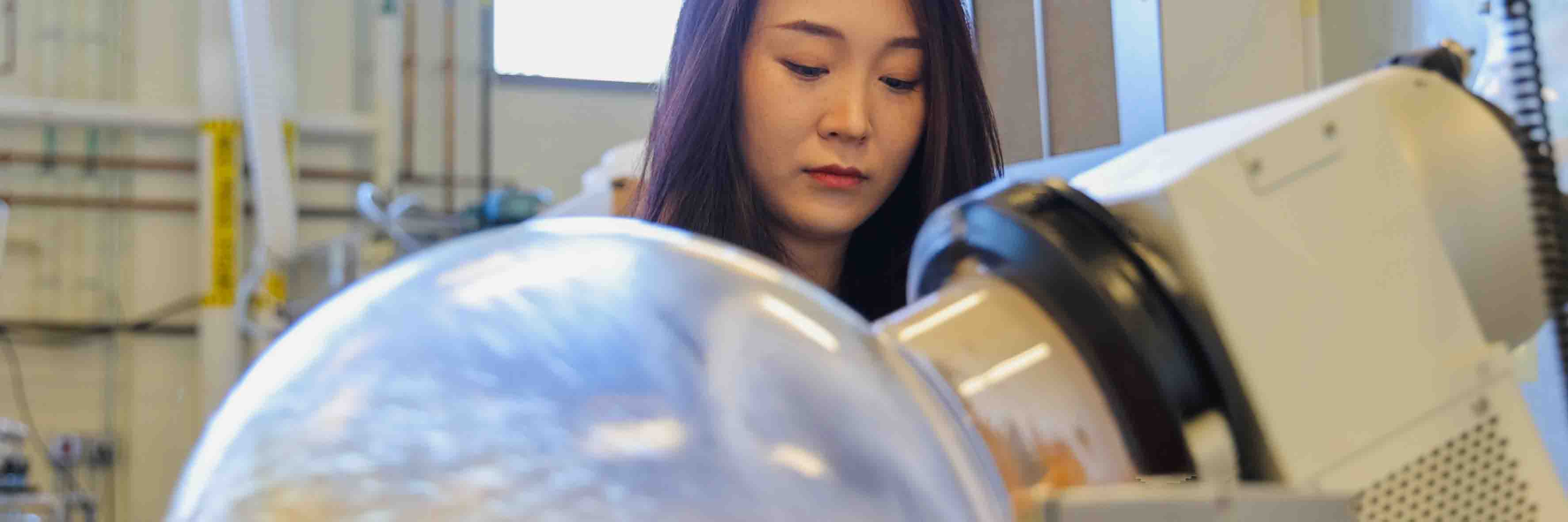 A researcher watches a ball filled with liquid spin in a machine.