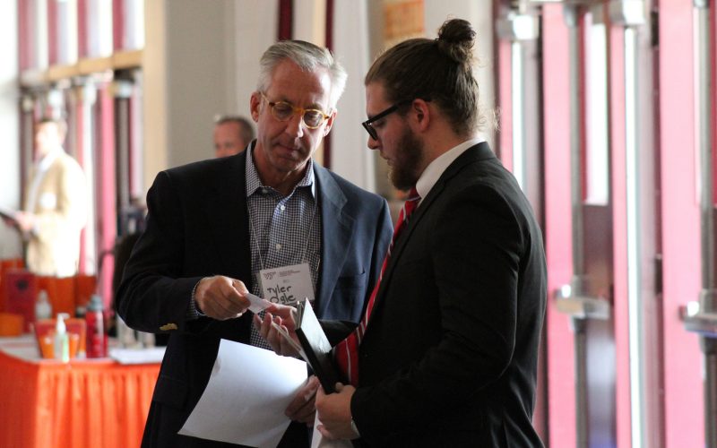 An employer handing a business card to a student at a career fair.