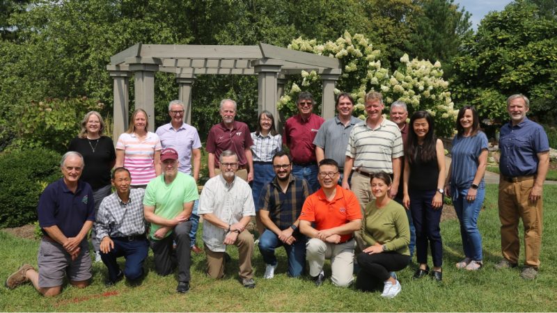 Sustainable biomaterials group standing and kneeling in a garden in front of a trellis