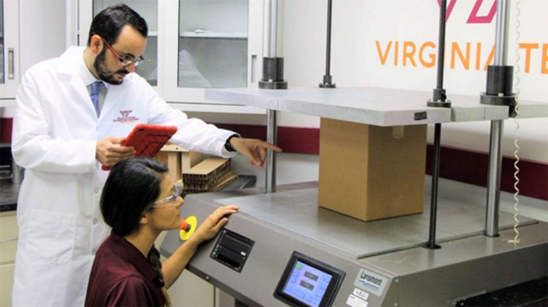 A professor and student running a test at a machine that measures load on a package.
