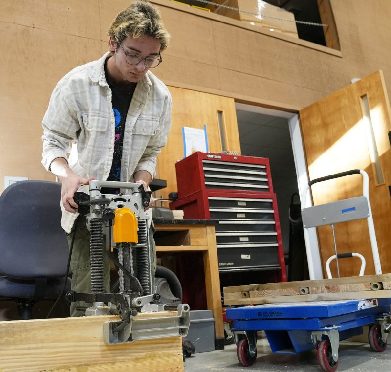 A student researcher uses a tool to make cuts into cross-laminated timber.